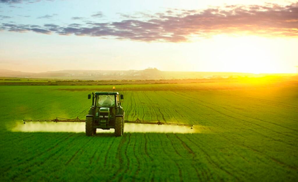 Tractor spraying a field of wheat with fertilizer